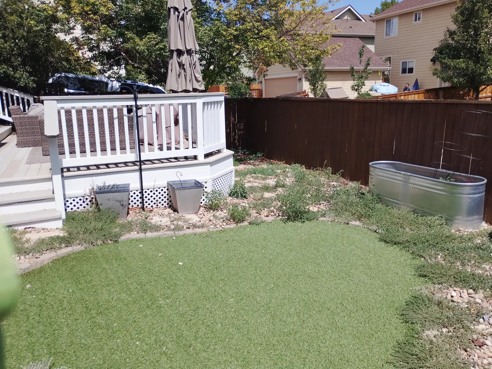 After: Cleared stone beds and tidy backyard with artificial turf and deck in Longmont, CO