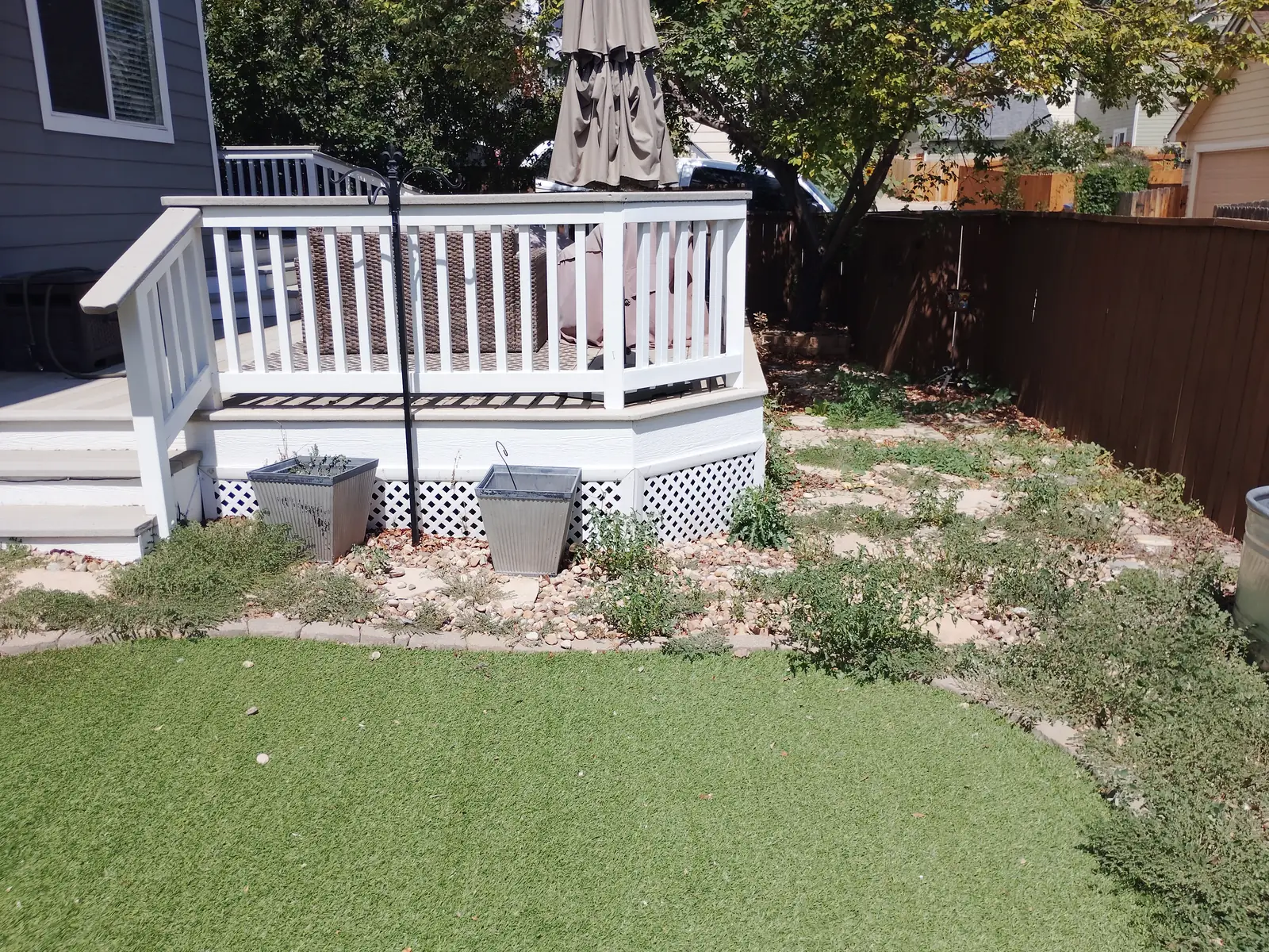 Backyard overview with artificial turf, stone beds, and deck