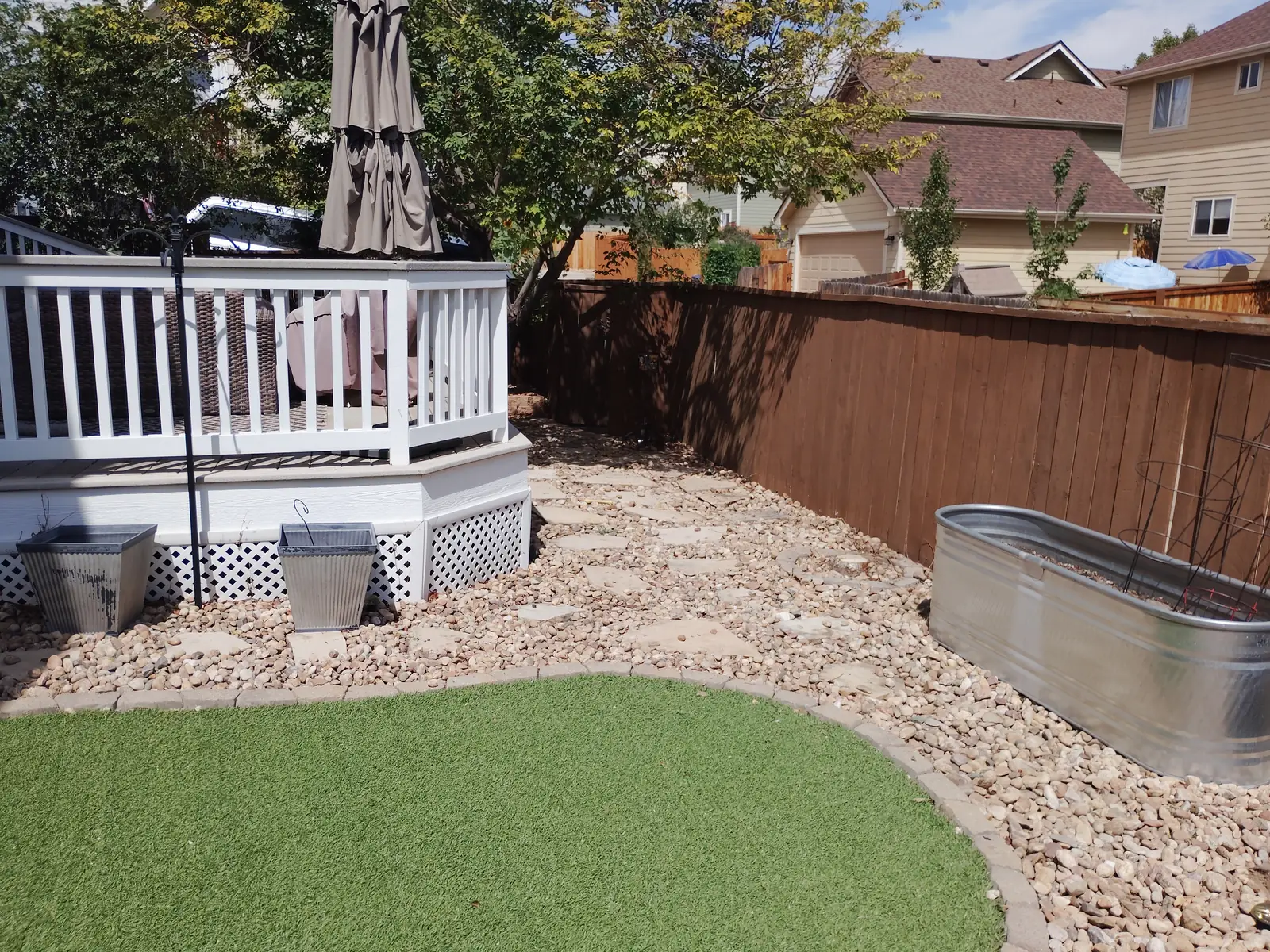 Before: Weeds and ground cover overtaking the stone garden beds along the fence in Longmont, CO